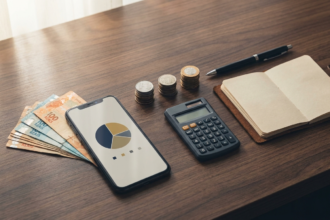 Mesa organizada com R$ 1.000 em cedulas, celular mostrando grafico de portfolio e moedas separadas em pilhas representando alocacao inicial